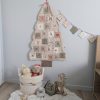 Calendrier de l'Avent mural en tissu clair en forme de sapin avec 24 poches numérotées, suspendu dans une chambre d'enfant. Panier en corde avec doudous et guirlande assortie.